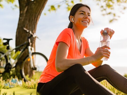 sonriente-mujer-hermosa-bebiendo-agua-botella-haciendo-deporte-manana-parque_285396-4388-e1611246858655.jpg