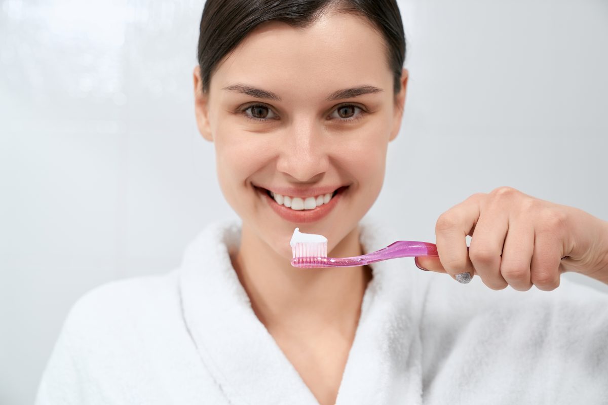 woman-in-white-robe-after-shower-holding-toothbrush-1200x800.jpg